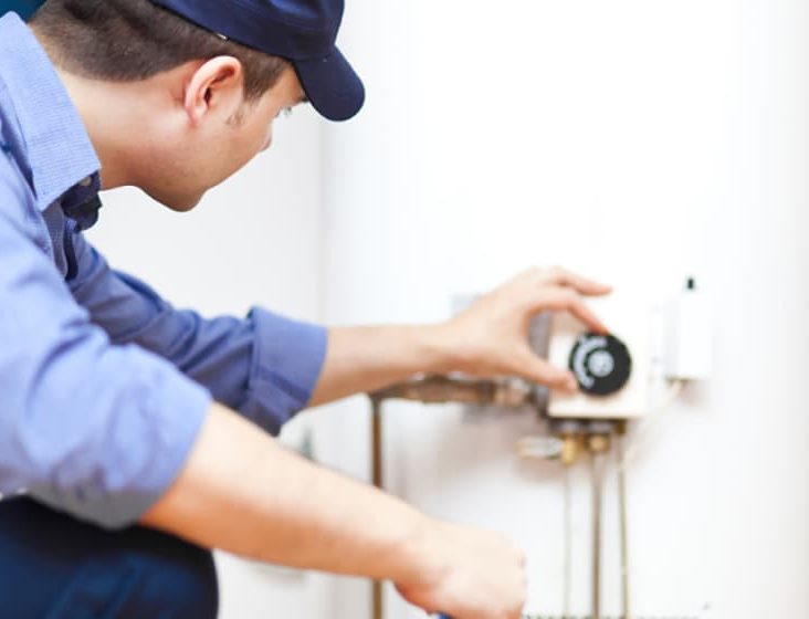Plumber adjusting heat setting for hot water — Plumbing Contractors in Brisbane, QLD