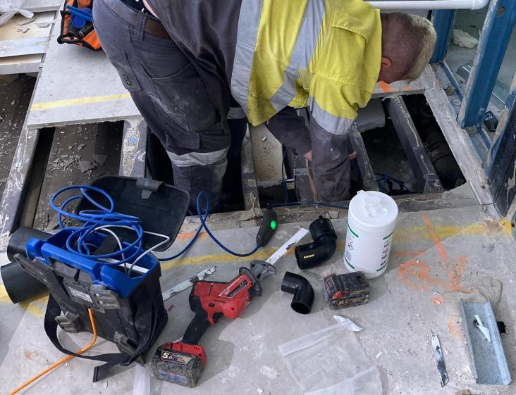 Plumber working on pipeline under the floor — Plumbing Contractors in Narangba, QLD