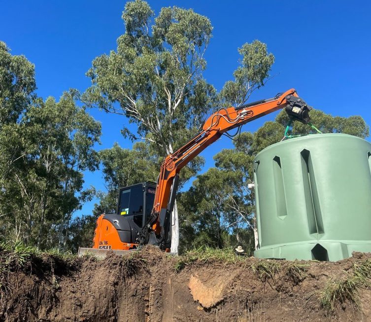 Excavator placing septic tank on the ground — Plumbing Contractors in Brisbane, QLD