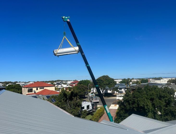 Crane carrying hot water tank — Plumbing Contractors in Brisbane, QLD