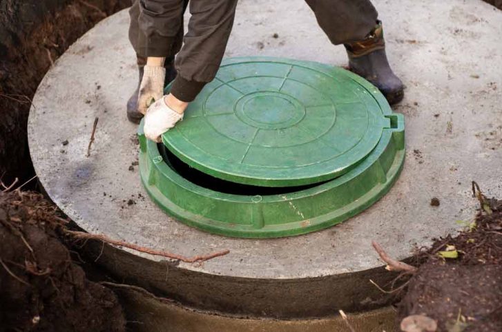 Worker Installs A Sewer Manhole On A Septic Tank
